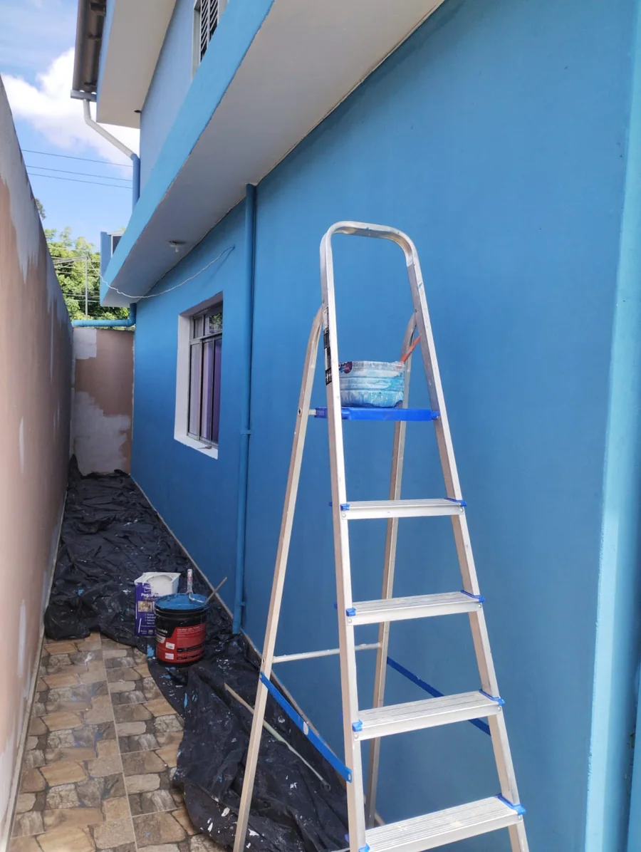 Depois: a mesma parede pintada de azul, com janela branca e escada
